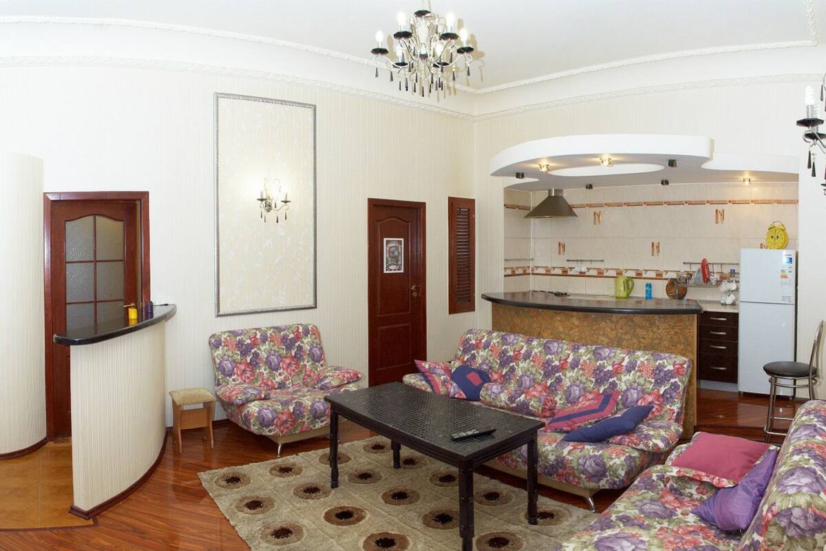 Uma sala de estar com sofá, mesa de centro e cozinha ao fundo.