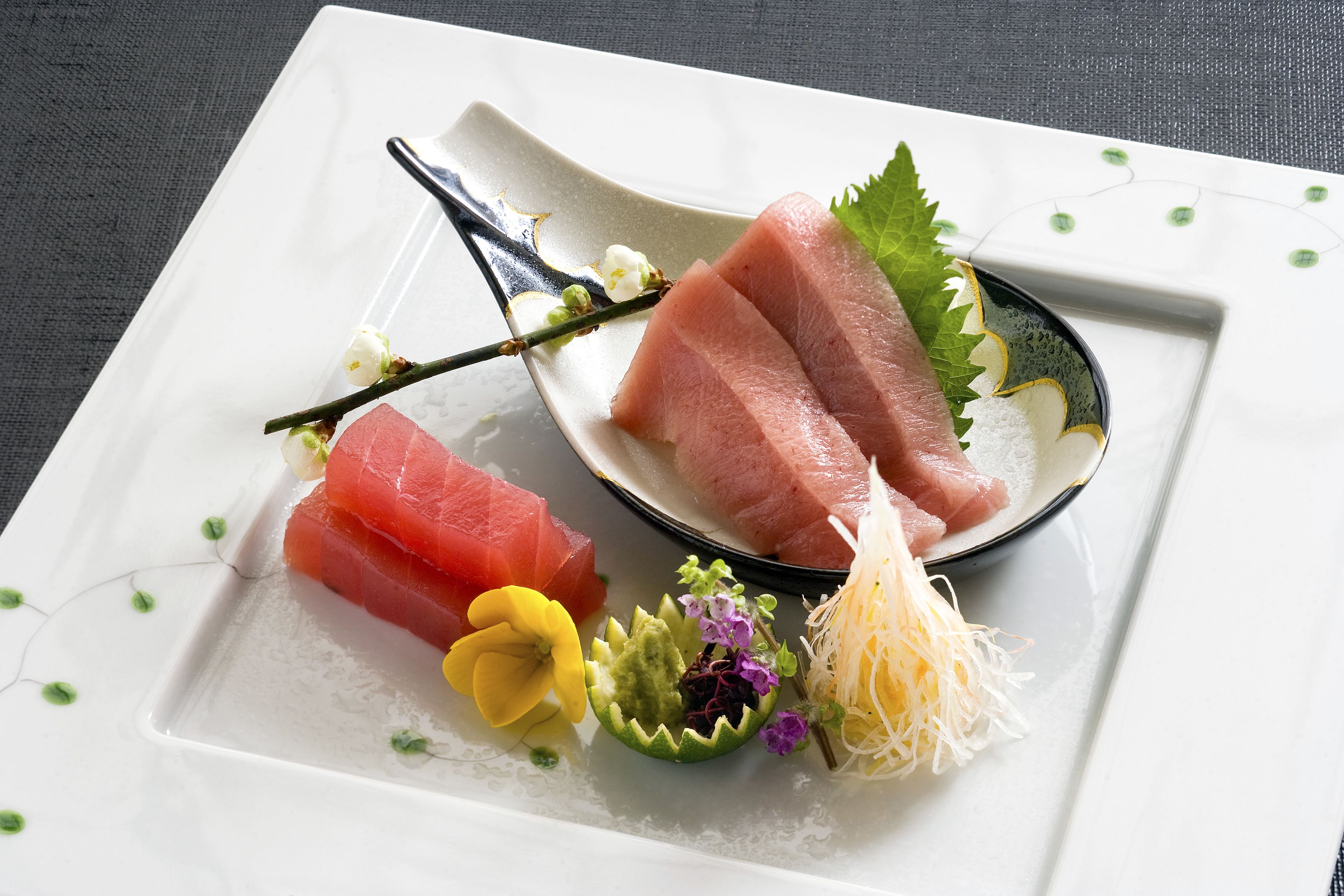 A plate with sashimi and a small bowl of wasabi.