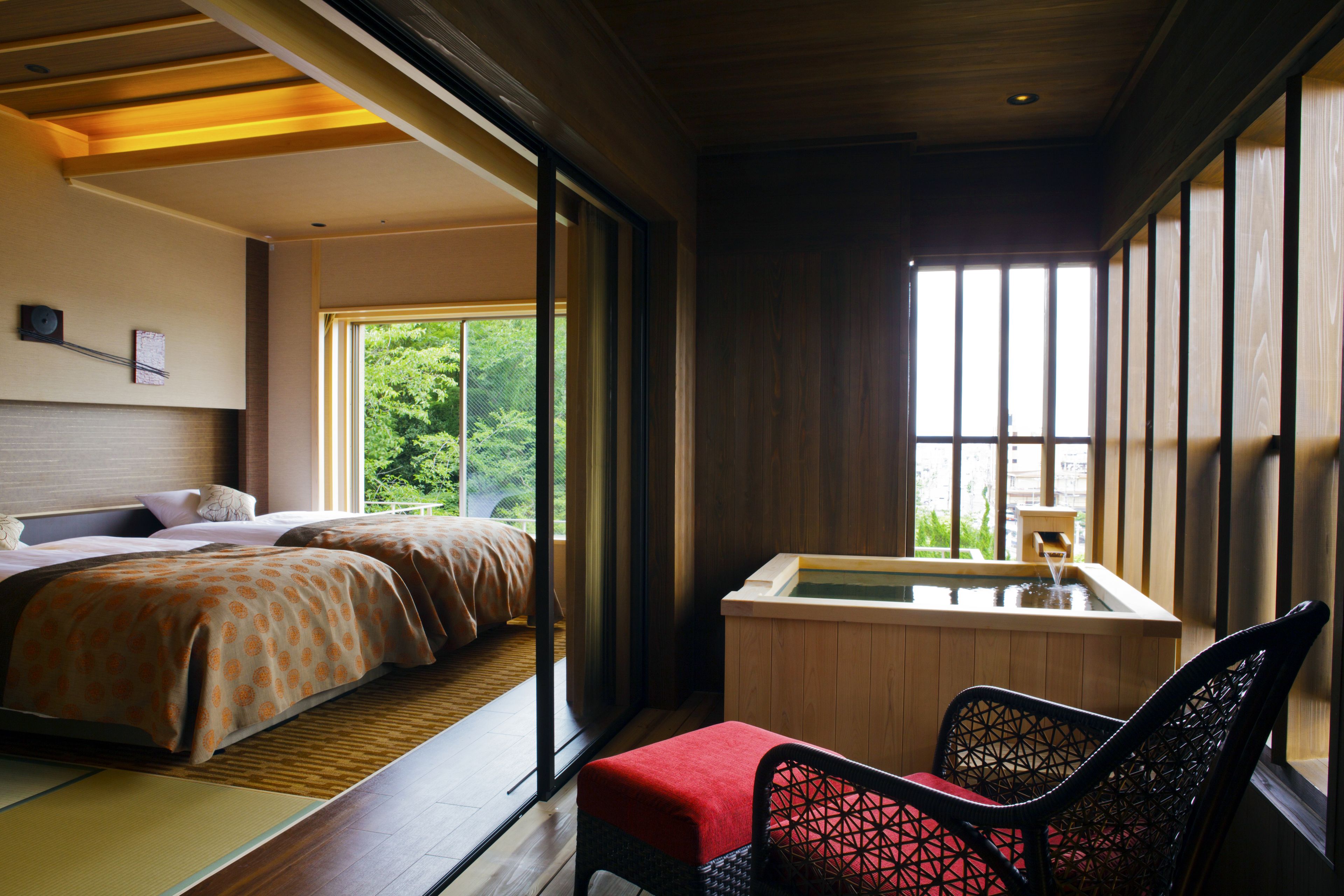 A traditional Japanese-style room with tatami flooring, a futon bed, a wooden bath, and a sliding door leading to a balcony.