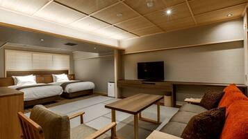 Una habitación de hotel con cama, sofá, televisor y escritorio.