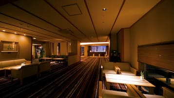 A hotel lobby with a striped carpet, seating areas, and a reception desk.