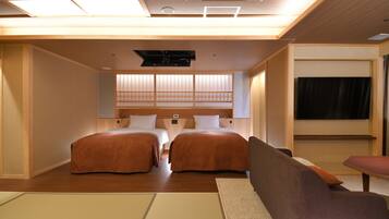 A hotel room with two beds, a sofa, a small table, and a traditional sliding door.