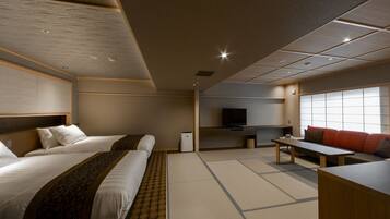 Habitación de hotel con dos camas, televisión, sofá, mesa y suelo de tatami.