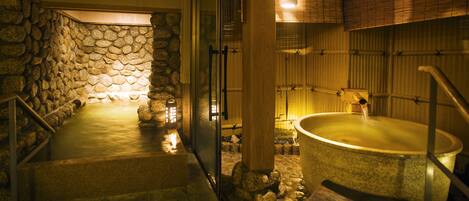 A stone-walled spa area with a hot tub and a stone bench.