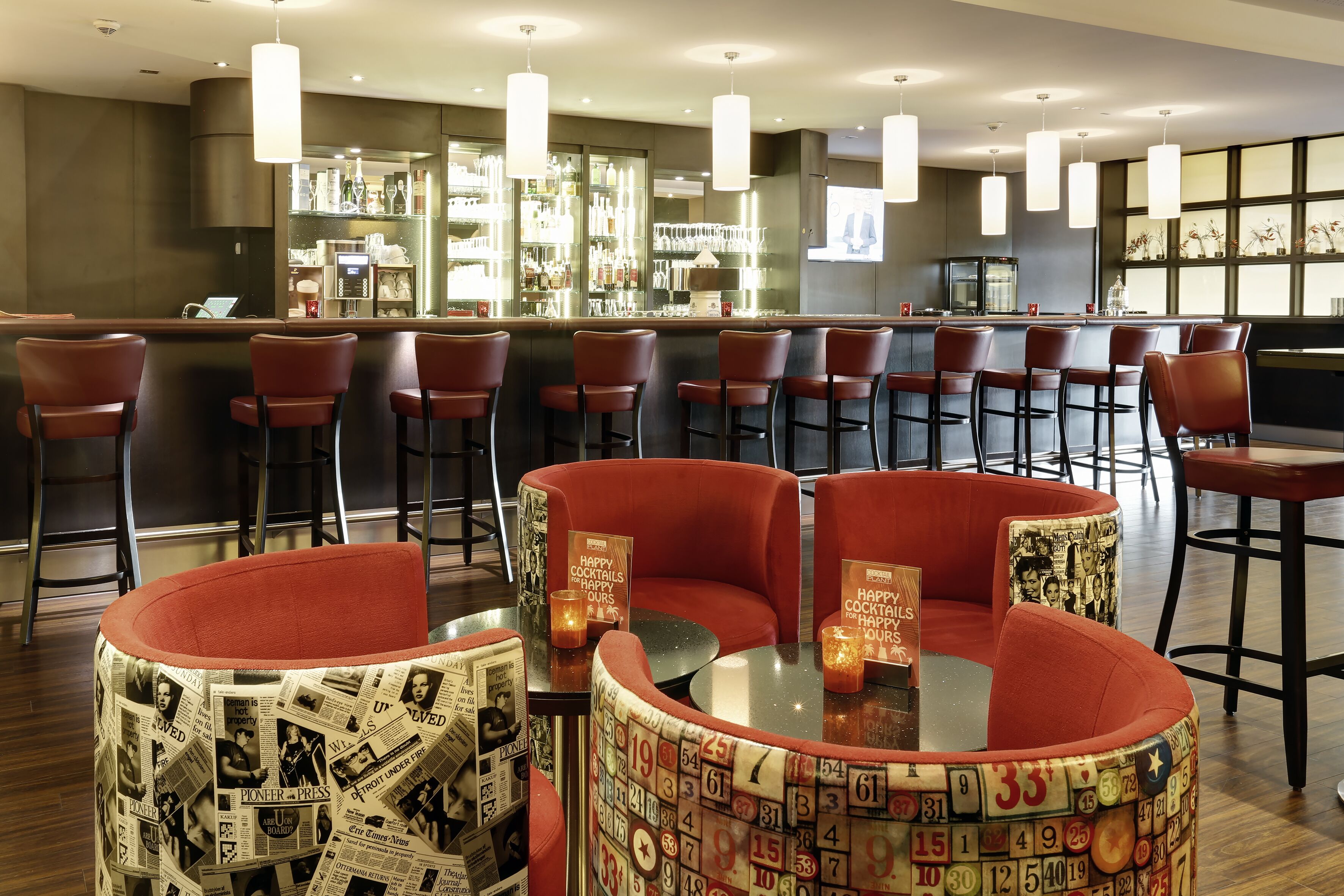 A bar area with red upholstered chairs, a bar counter, and a seating area with a patterned ottoman.