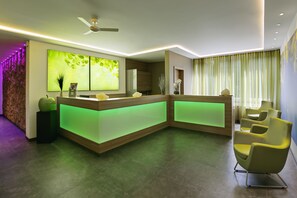 Un espace d’accueil moderne avec un comptoir incurvé, un éclairage d’ambiance vert et un ventilateur de plafond.