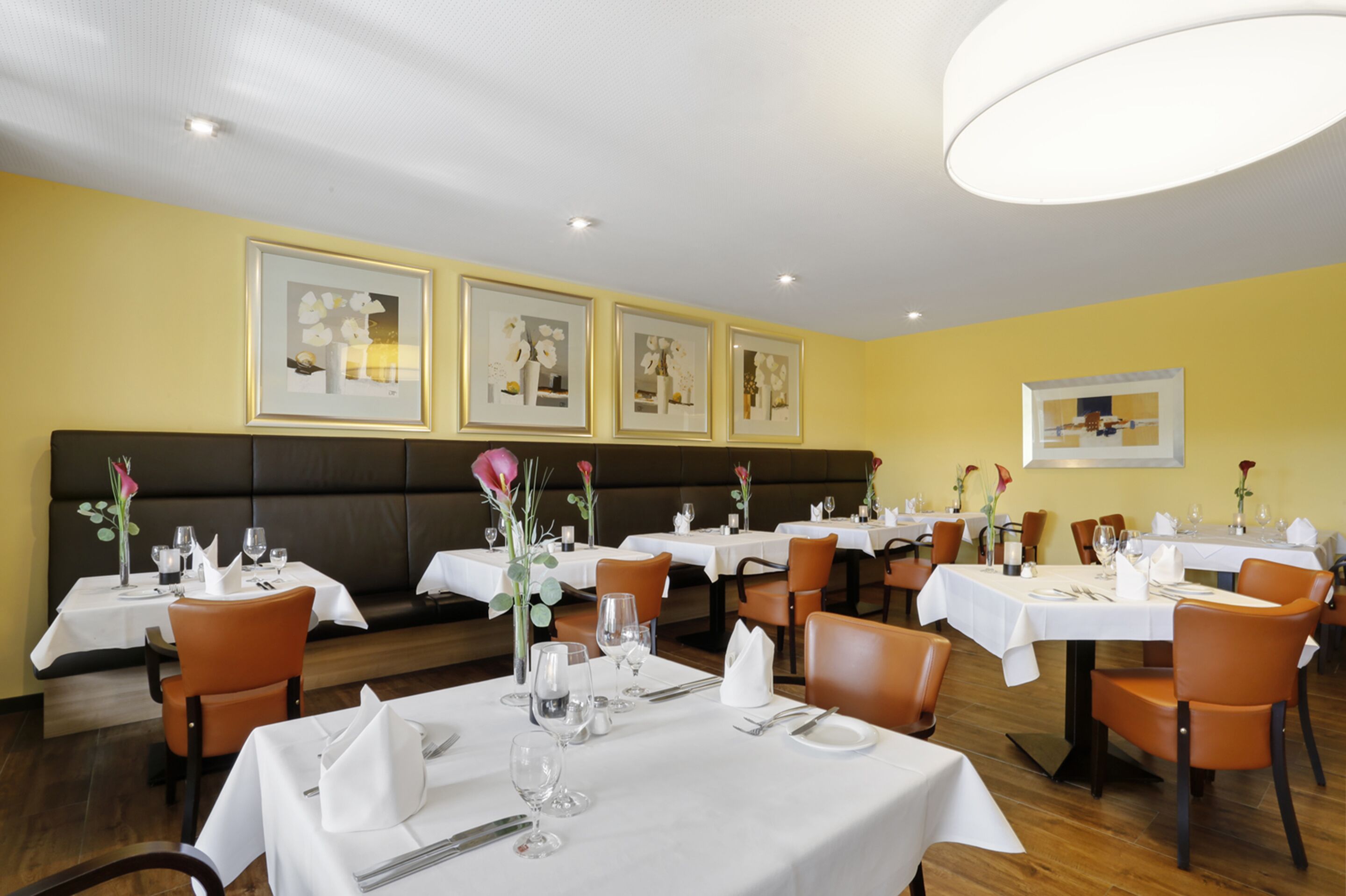 En restaurant med flere borde, stole og billeder i rammer på væggene.