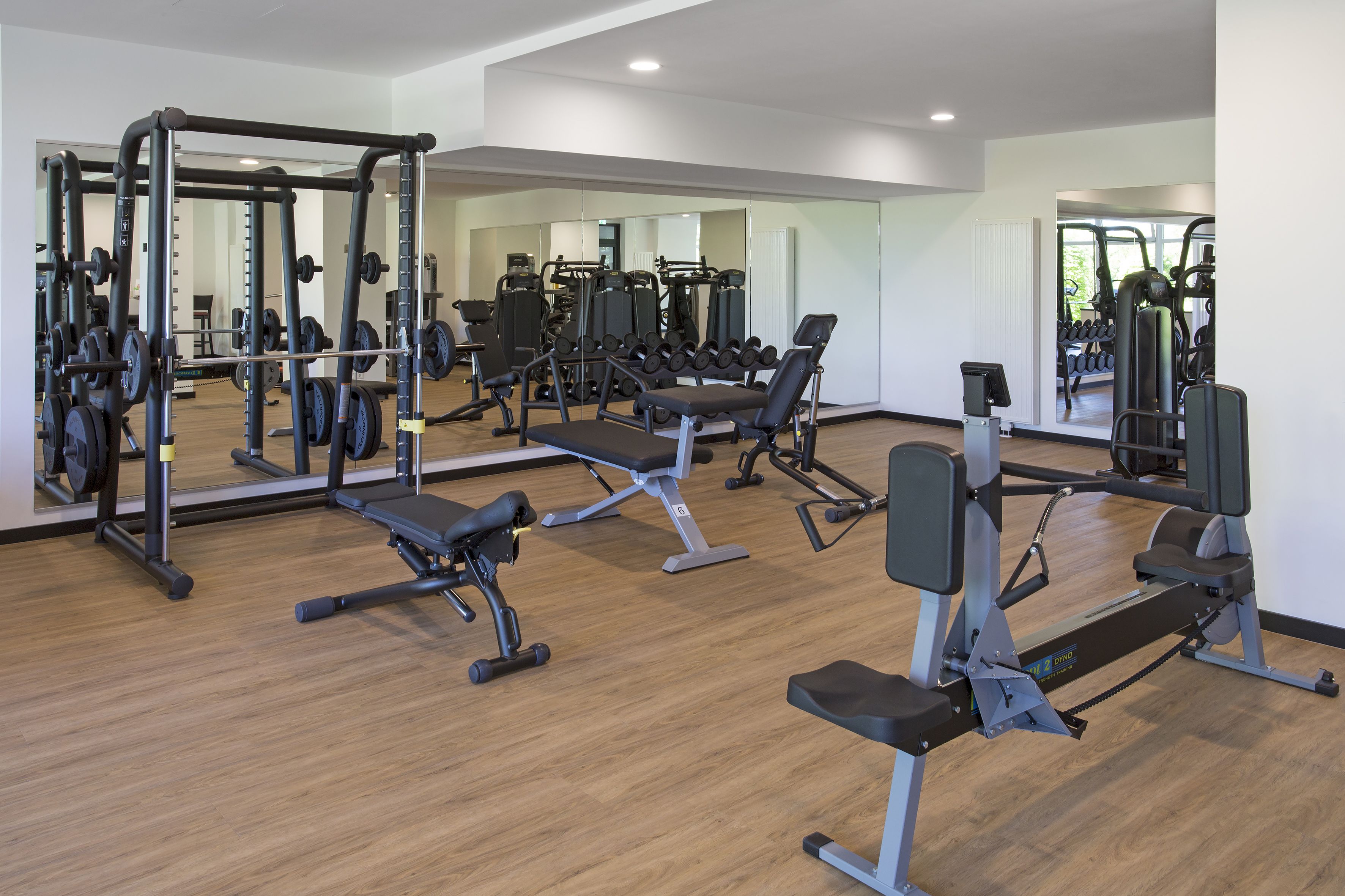 A gym with various exercise equipment, including weight machines, benches, and free weights.