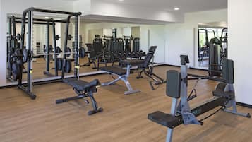 A gym with various exercise equipment, including weight machines, benches, and free weights.