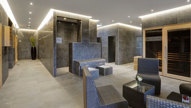 Un hall d’entrée moderne avec un comptoir d’accueil, un espace salon et un panneau indiquant la présence d’un spa.