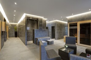 Eine moderne Lobby mit Empfangsschalter, Sitzbereich und Hinweisschild für das Spa.