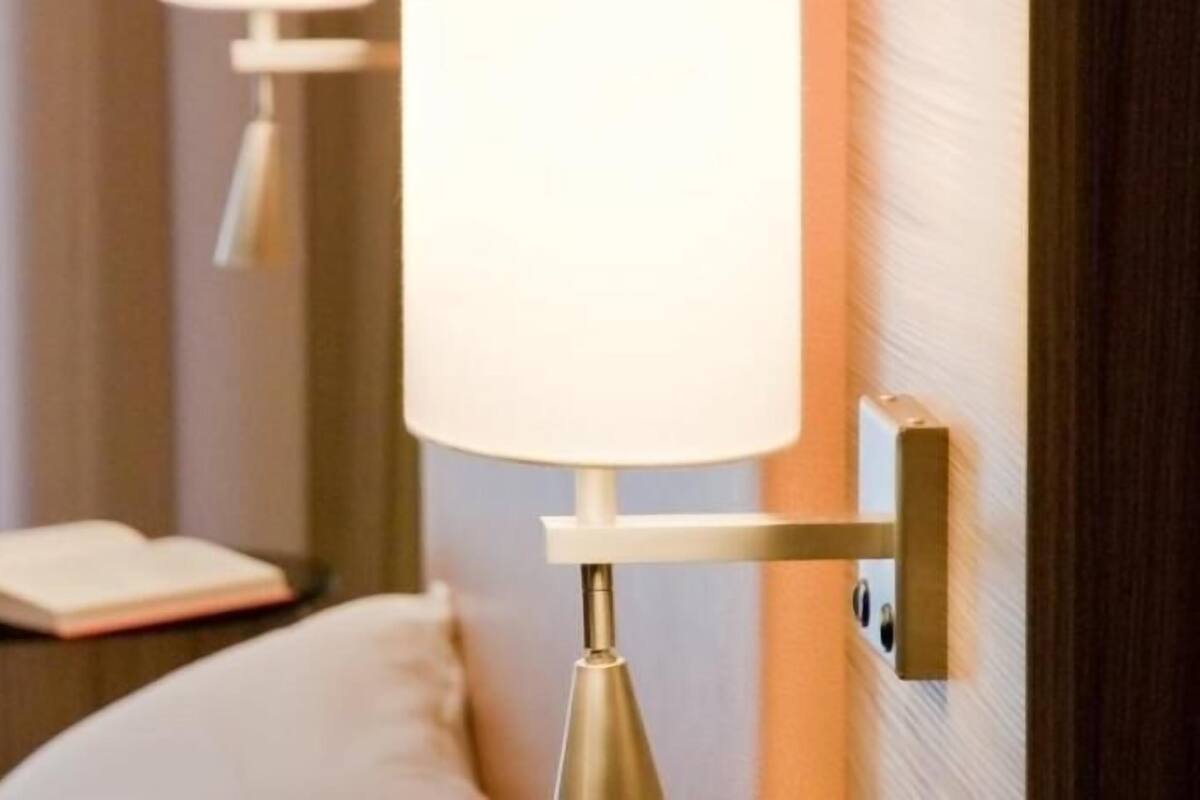 Habitació d'hotel amb una làmpada de nit, una tauleta de nit i un llibre obert.
