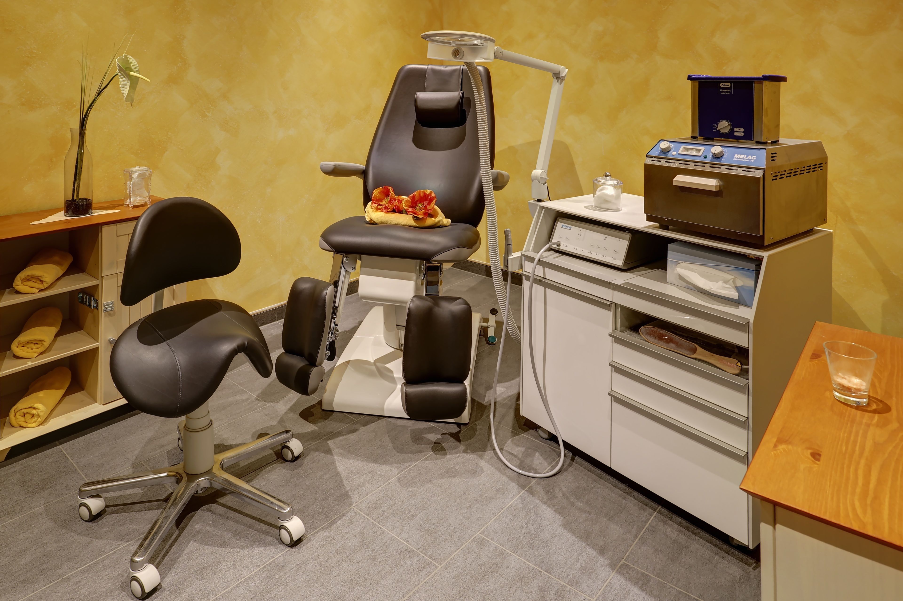 Una clínica dental con un sillón odontológico, un equipo de esterilización y una estantería con toallas dobladas.