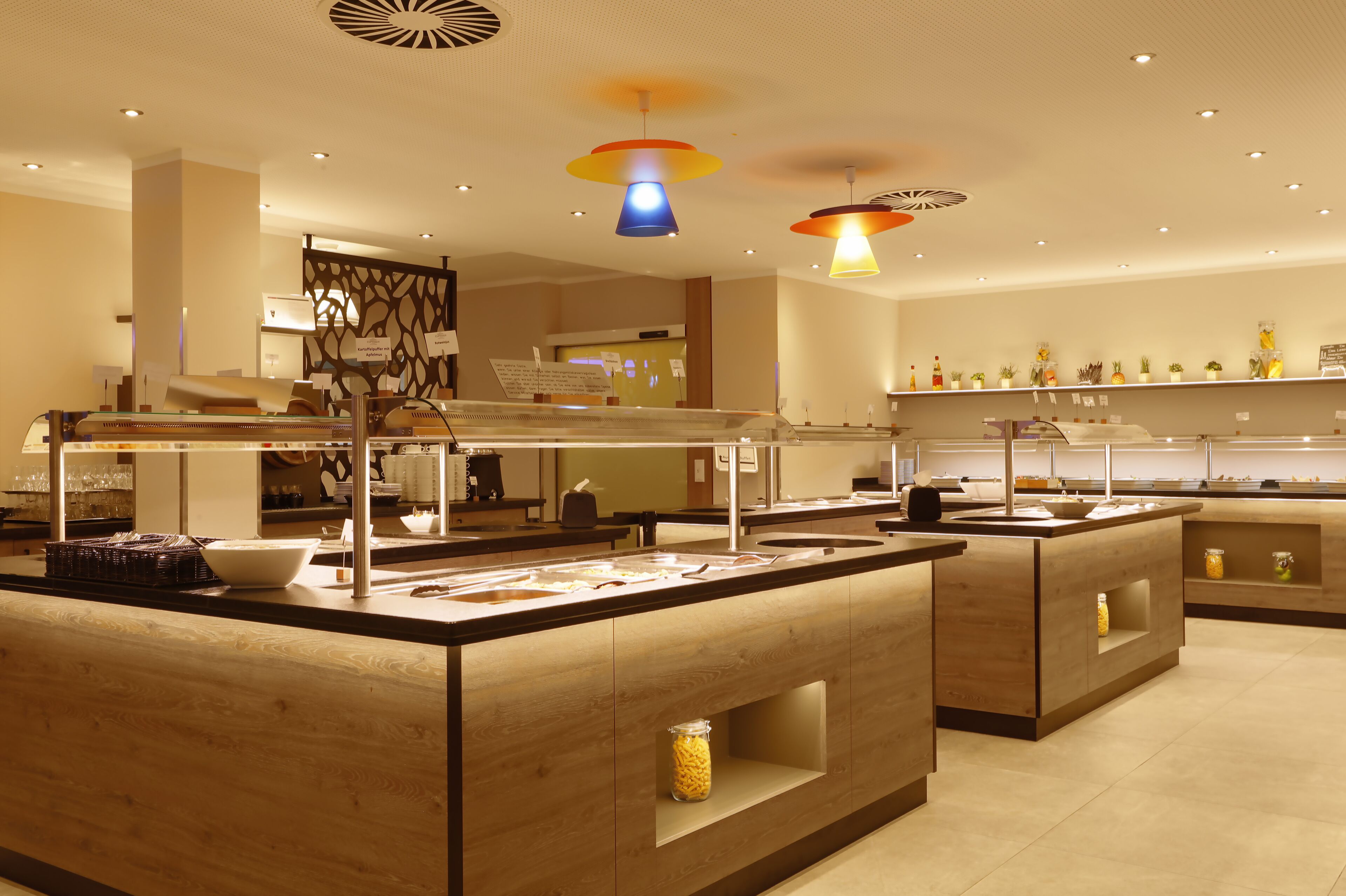 Uma área de buffet moderna com várias estações de serviço, uma apresentação central e uma variedade de alimentos.