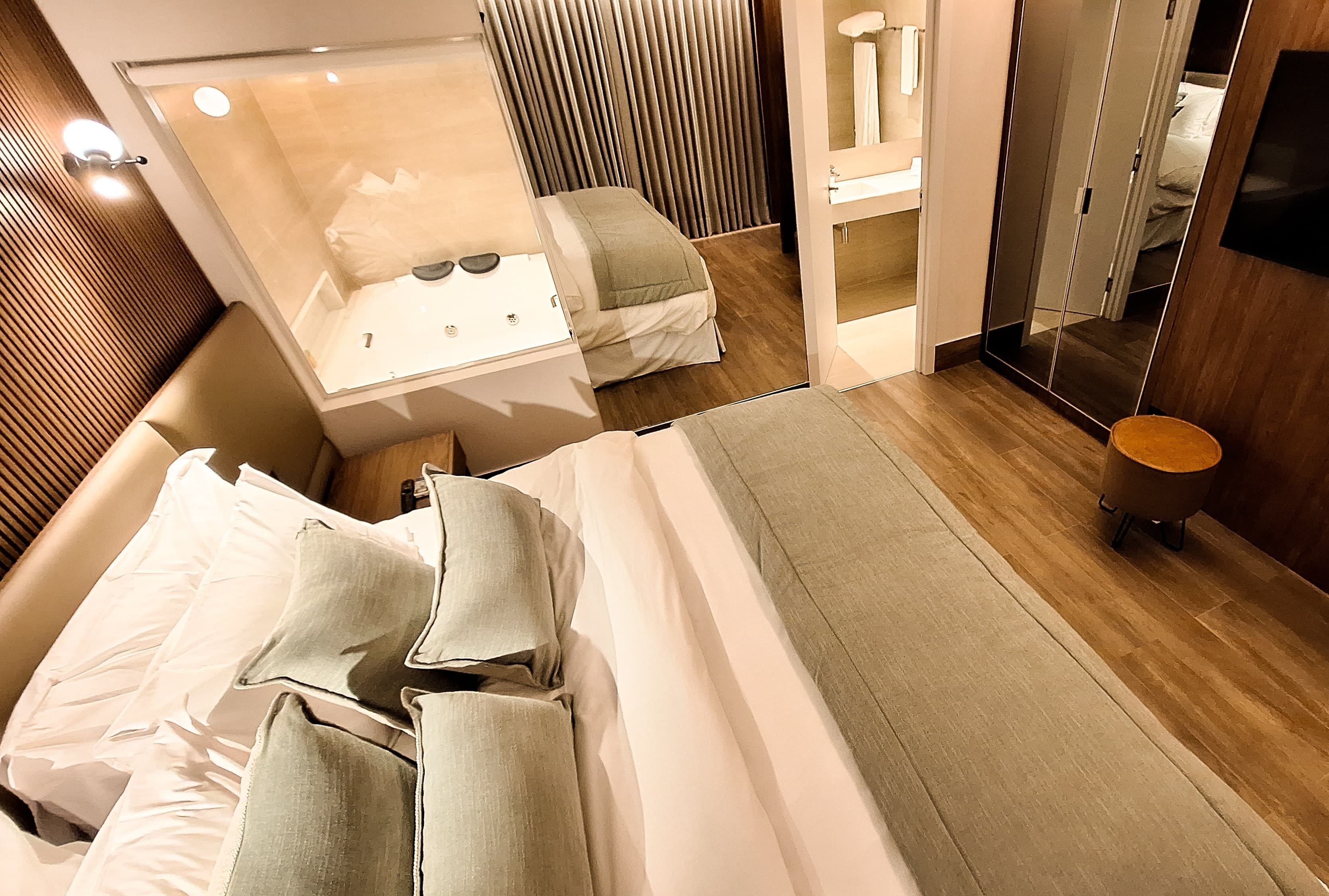 A modern hotel room with a large bed, a separate bathroom with a bathtub, and a mirror cabinet.