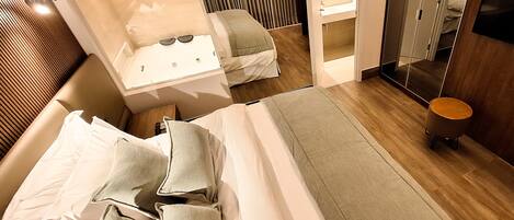 A modern hotel room with a large bed, a separate bathroom with a bathtub, and a mirror cabinet.