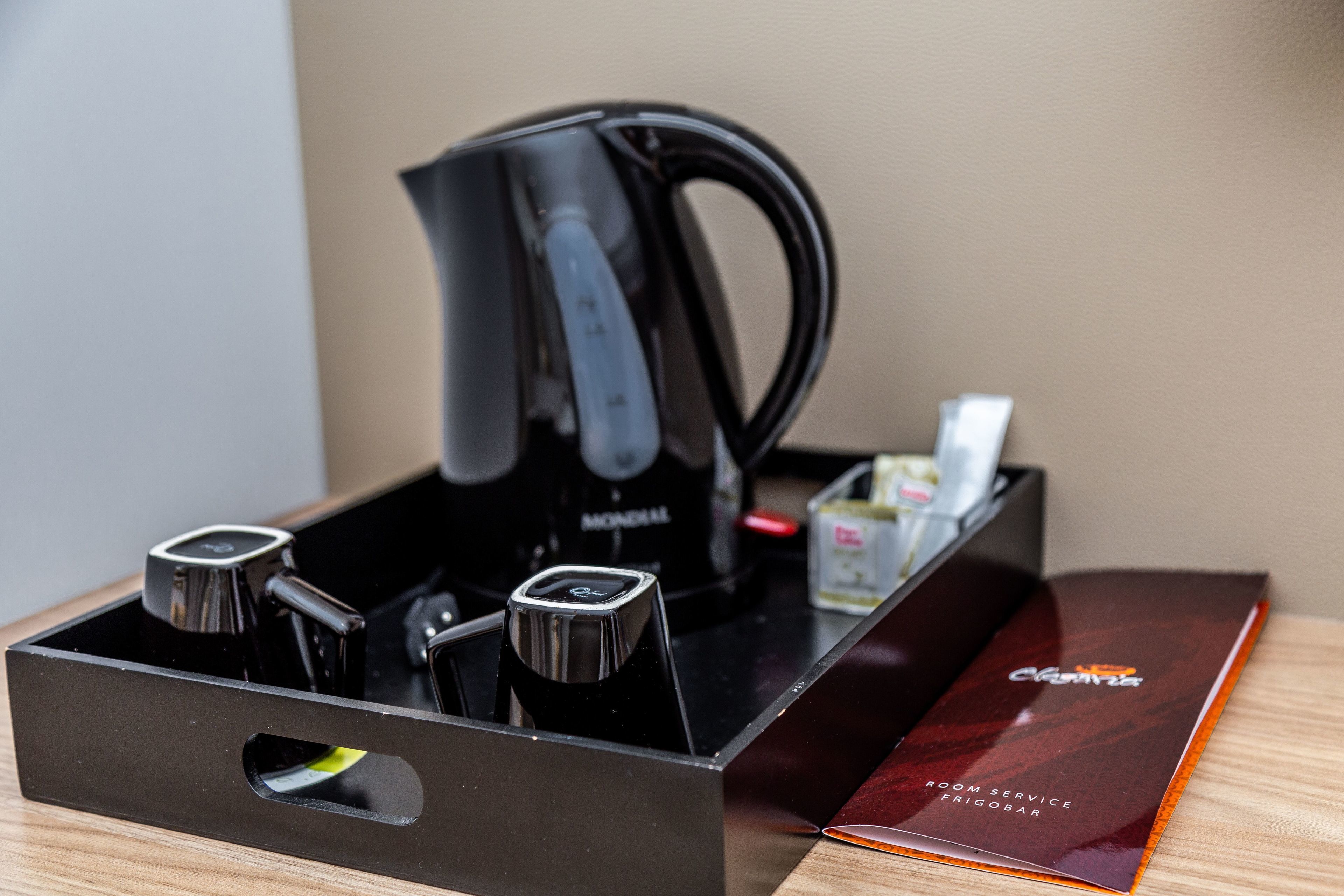 A black coffee maker in a drawer, a Monclai espresso machine, and a room service menu.