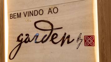 Um letreiro com o texto 'BEM VINDO AO garden by' e um logotipo.