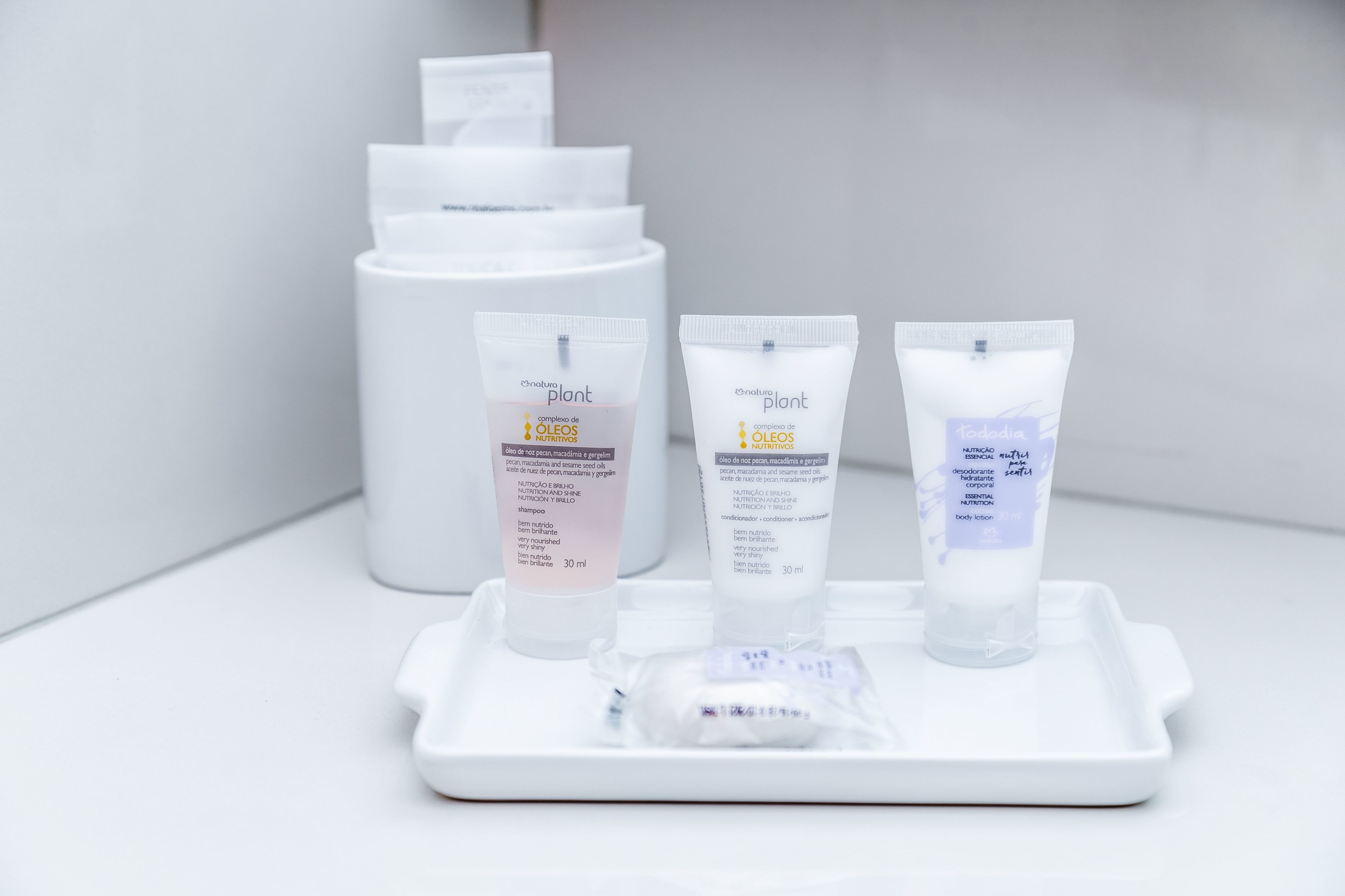 Three skincare tubes on a tray with a larger container in the background.