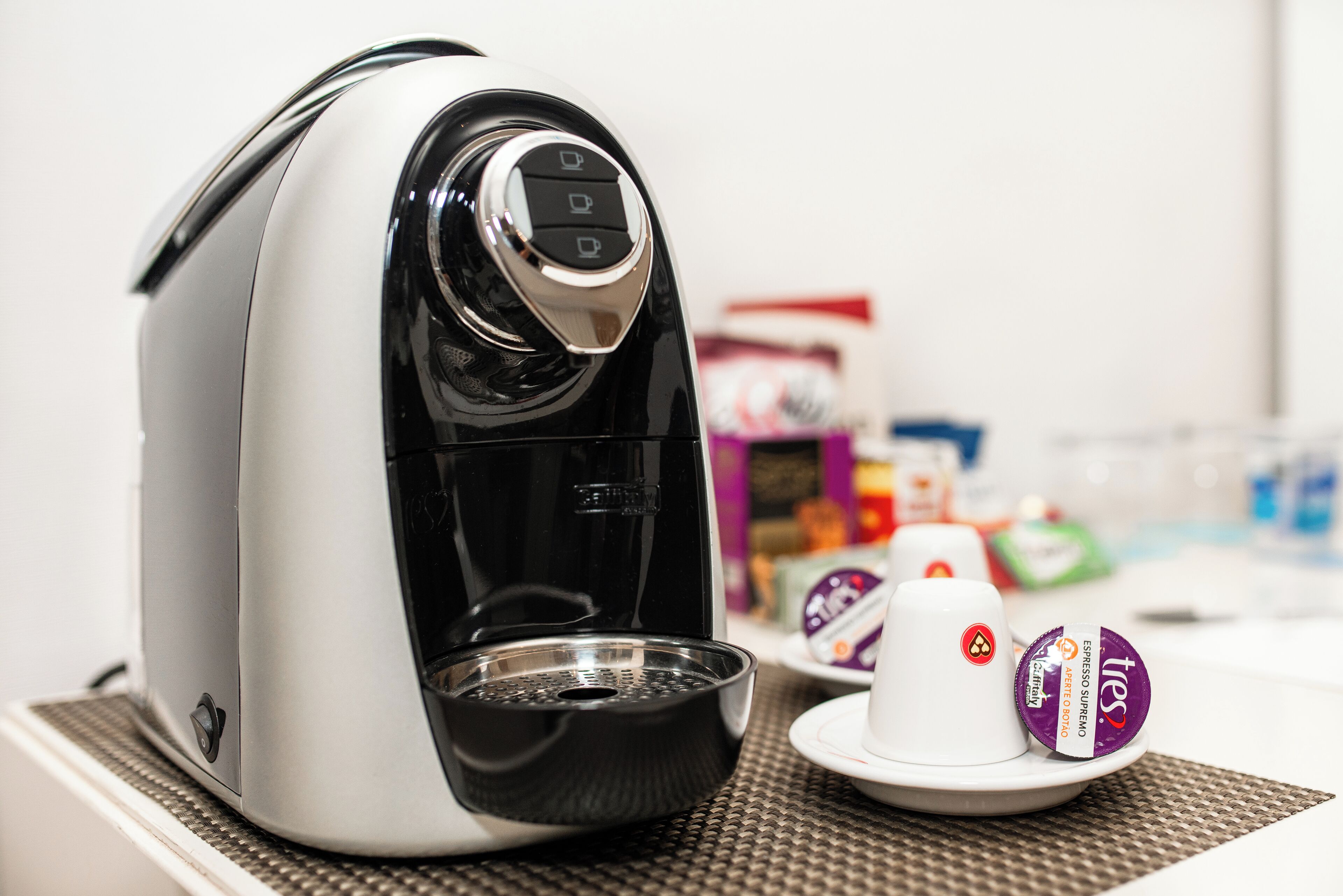 A coffee machine with a cup and a coffee pod on a table.