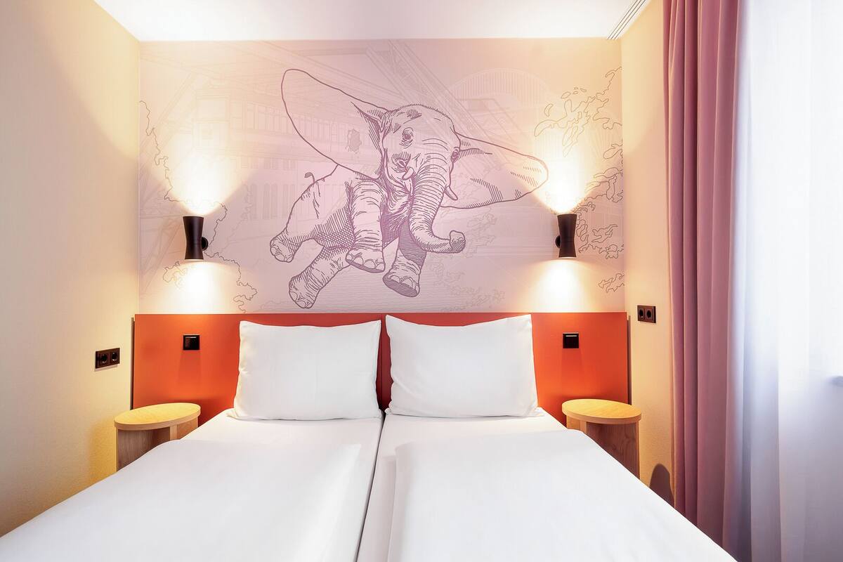Ein Hotelzimmer mit einem großen Bett, zwei Nachttischen und einem Wandbild.