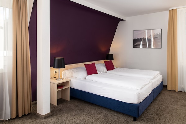 A hotel room with a large bed, two bedside lamps, a small table, and a painting on the wall. - Boutique Hotel Société (Baden-Baden)
