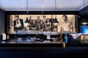 Zona de bar con un cartel grande que muestra a un grupo de personas, vasos y botellas.