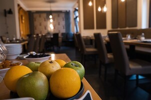 Un área de comedor con mesas y sillas, un cuenco de fruta sobre la mesa, y vista del interior del restaurante.