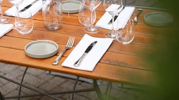 Uma mesa de madeira posta para uma refeição, com pratos, talheres e copos de vinho.