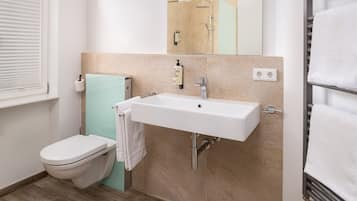 Een moderne badkamer met toilet, wastafel en douche.