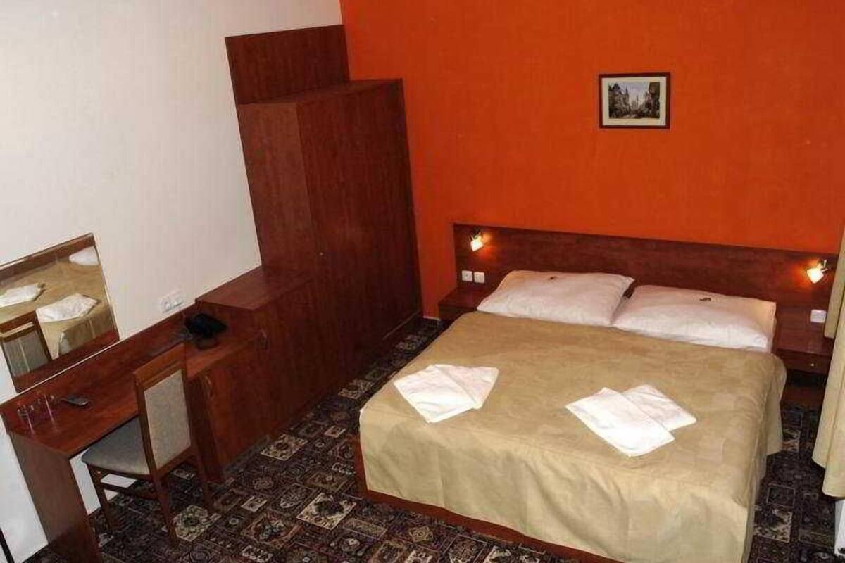 A hotel room with a bed, a desk, a chair, and a mirror.