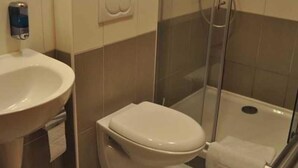 A bathroom with a toilet, a sink, and a glass-enclosed shower area. - City Central (Prague)