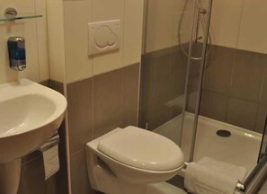 Un baño con lavamanos, inodoro y ducha.