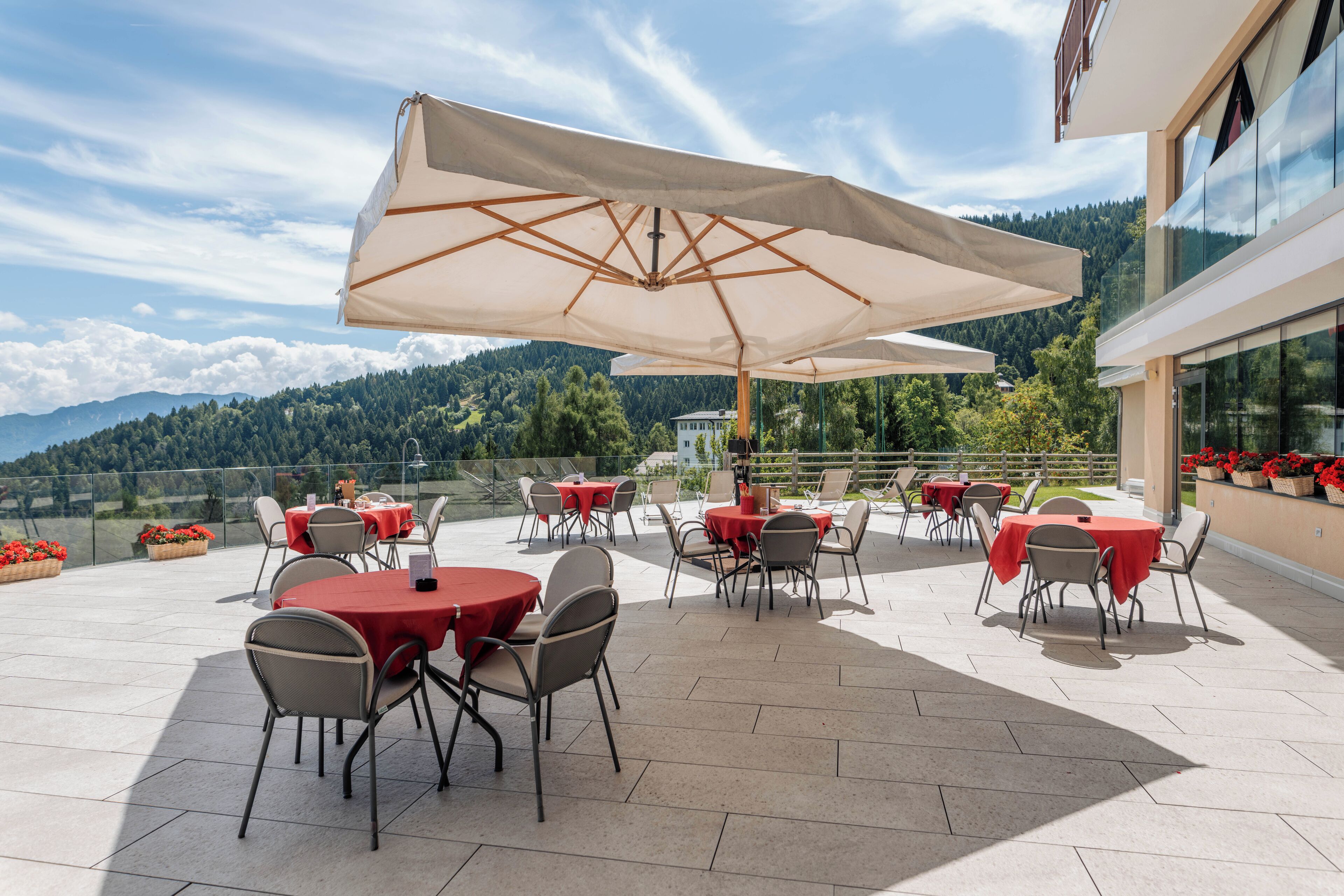 An outdoor patio with round tables and chairs, large umbrellas, and a scenic mountain view.
