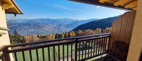 A balcony with a view of mountains and a sports field.