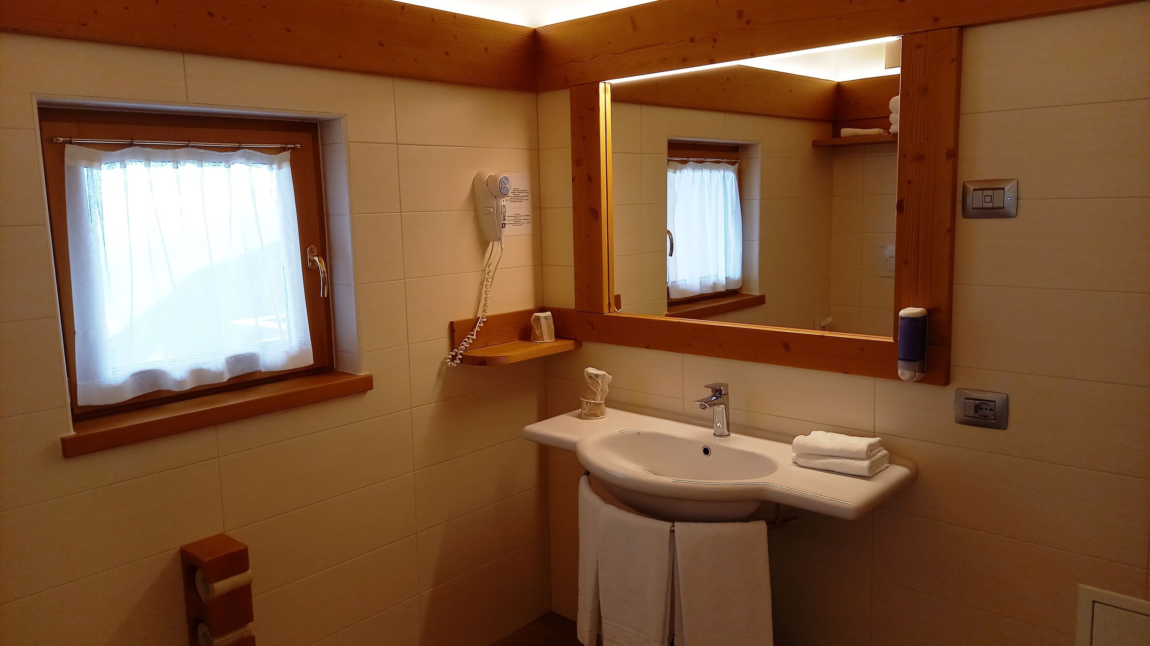 A bathroom with a sink, mirror, and window.