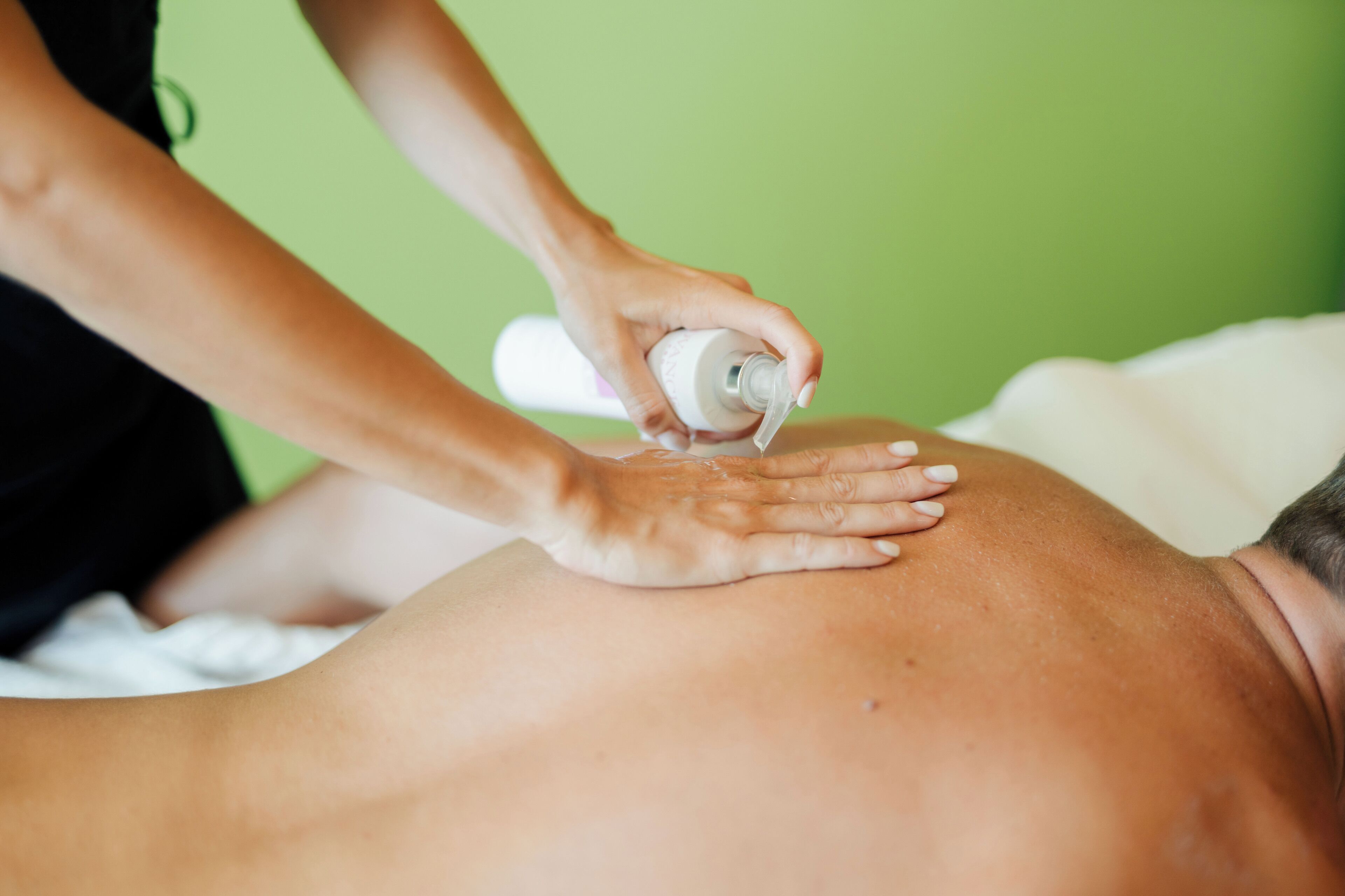 A massage therapy session with a green background.