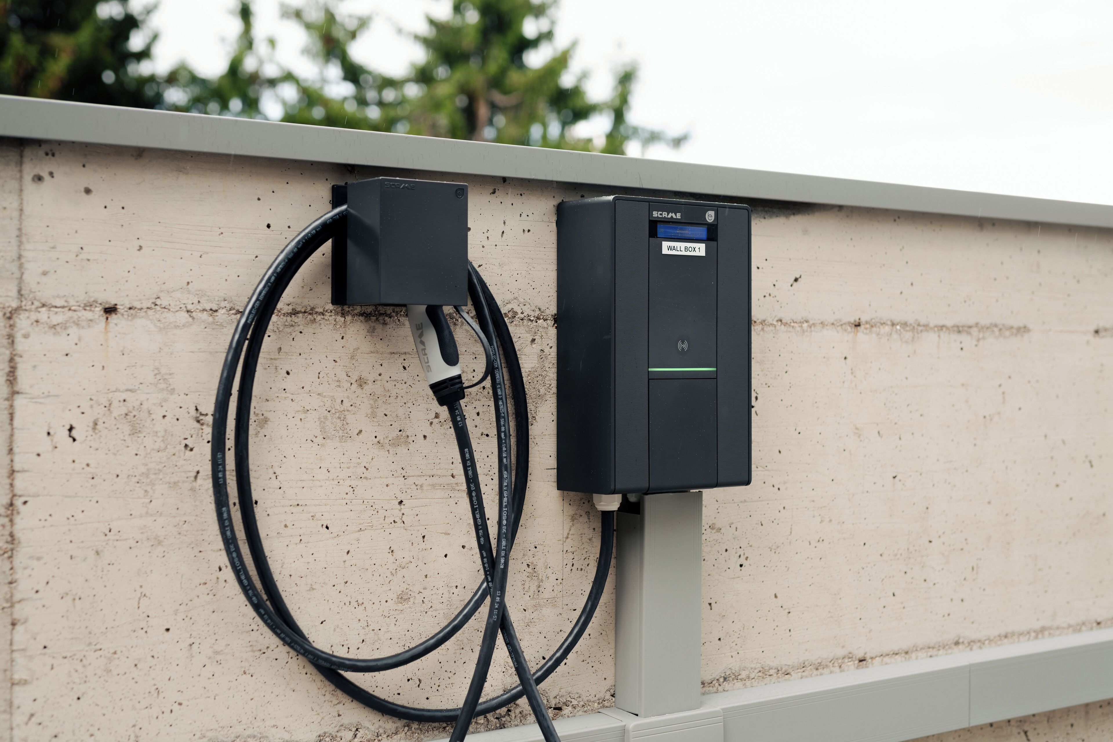 Een buitenvochtige elektriciteitskast met een aangesloten kabel, bevestigd aan een muur.