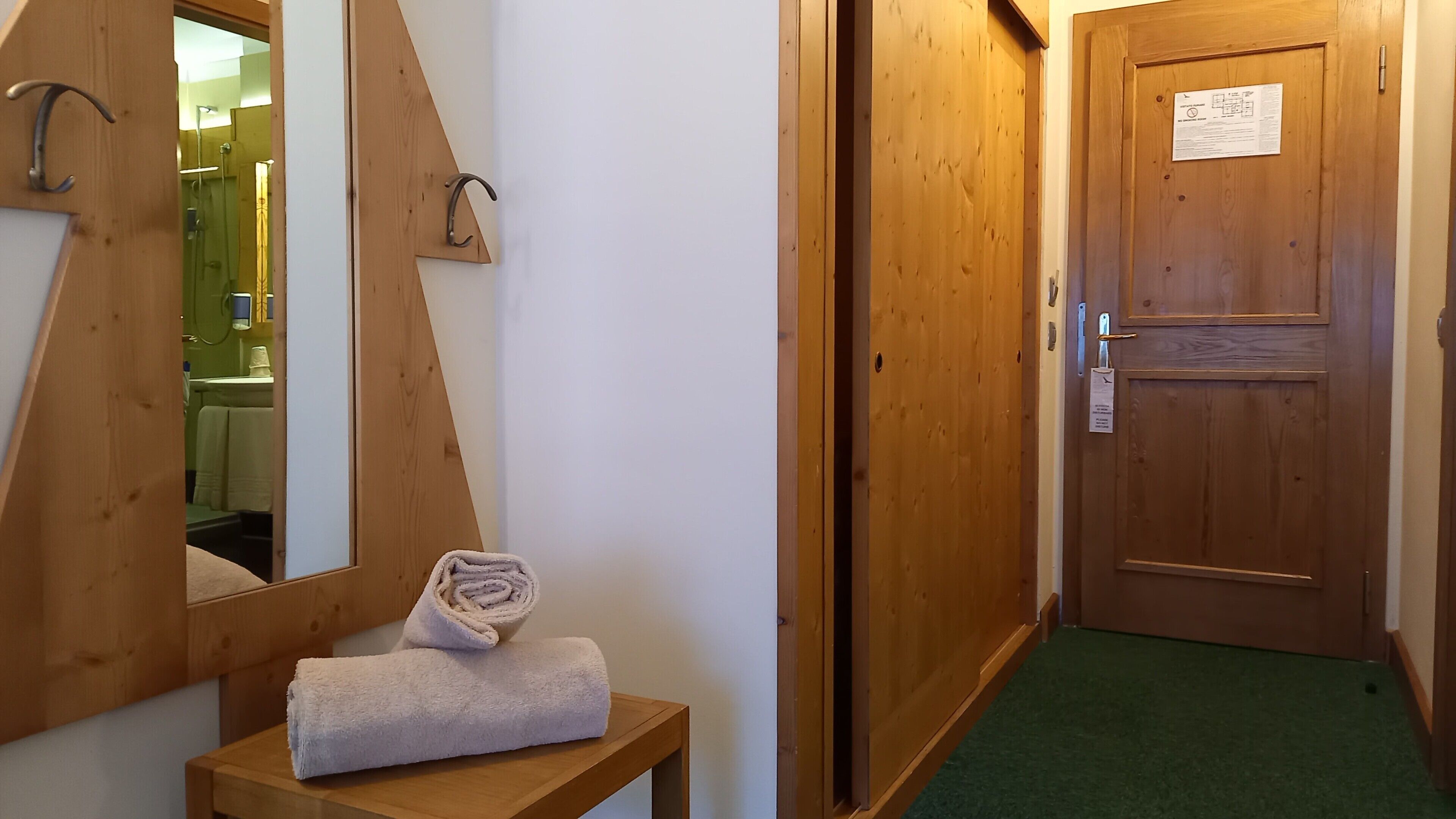 A wooden door with a sign, a mirror, and a towel on a small table.