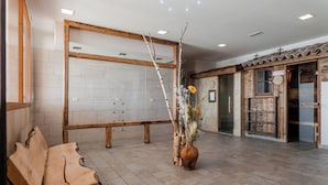 Un área de recepción con un banco de madera, un jarrón con flores y una pared de azulejos.