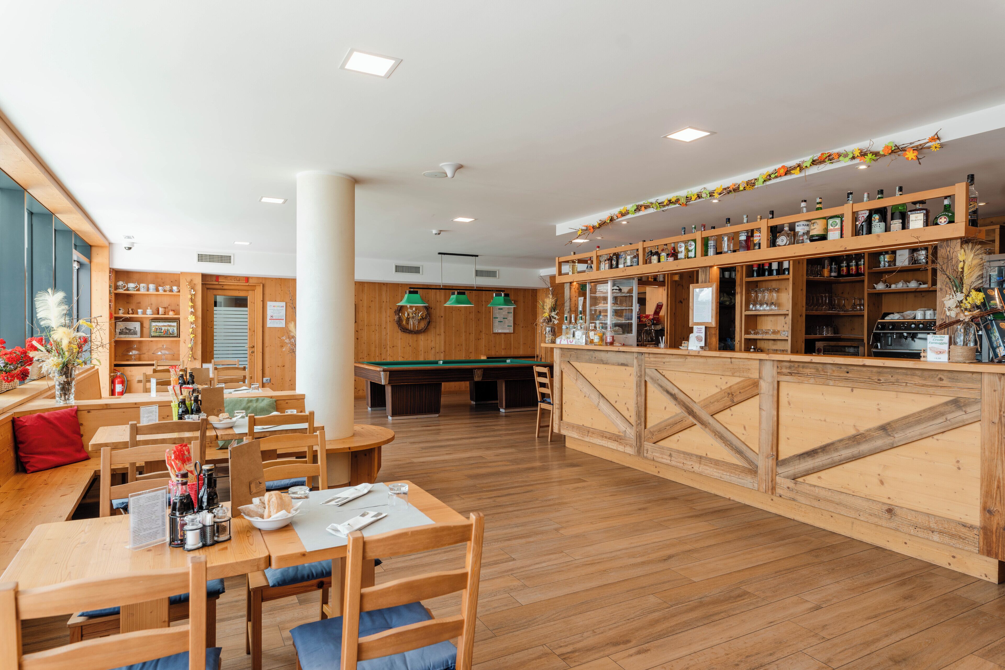 Ein Restaurant mit Holzkubaturen, einem Billardtisch und einer Bar mit Regalen voller Flaschen.