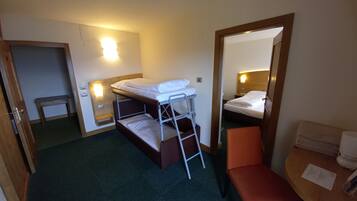 Una camera d'albergo compatta con un letto a castello, una piccola panca, un comodino e uno specchio.