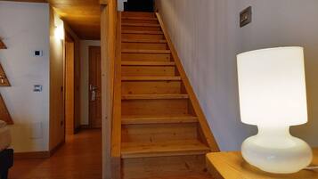 Una escalera de madera con una lámpara en el descansillo.
