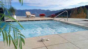 Area piscina con vista sulle montagne, una sedia a sdraio e una pianta in vaso.