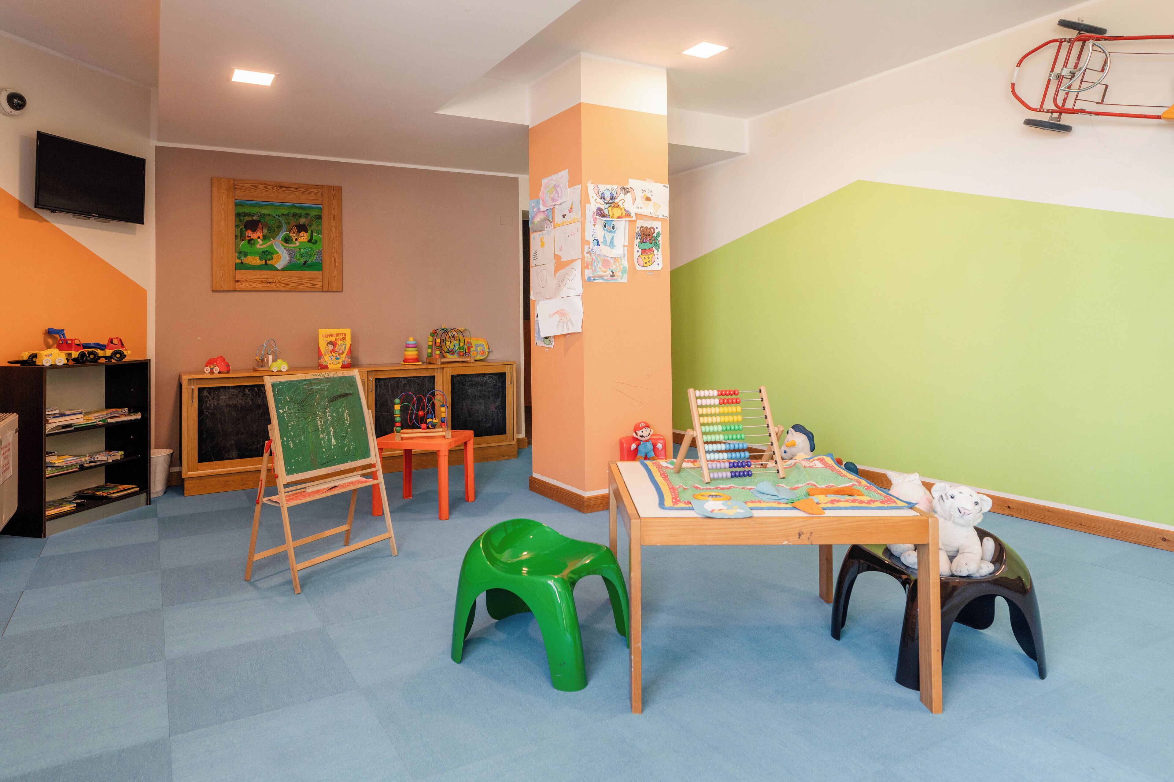 A children's playroom with a chalkboard, toys, and a table with educational materials.