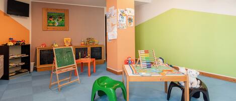 A children's playroom with a chalkboard, toys, and a table with educational materials.