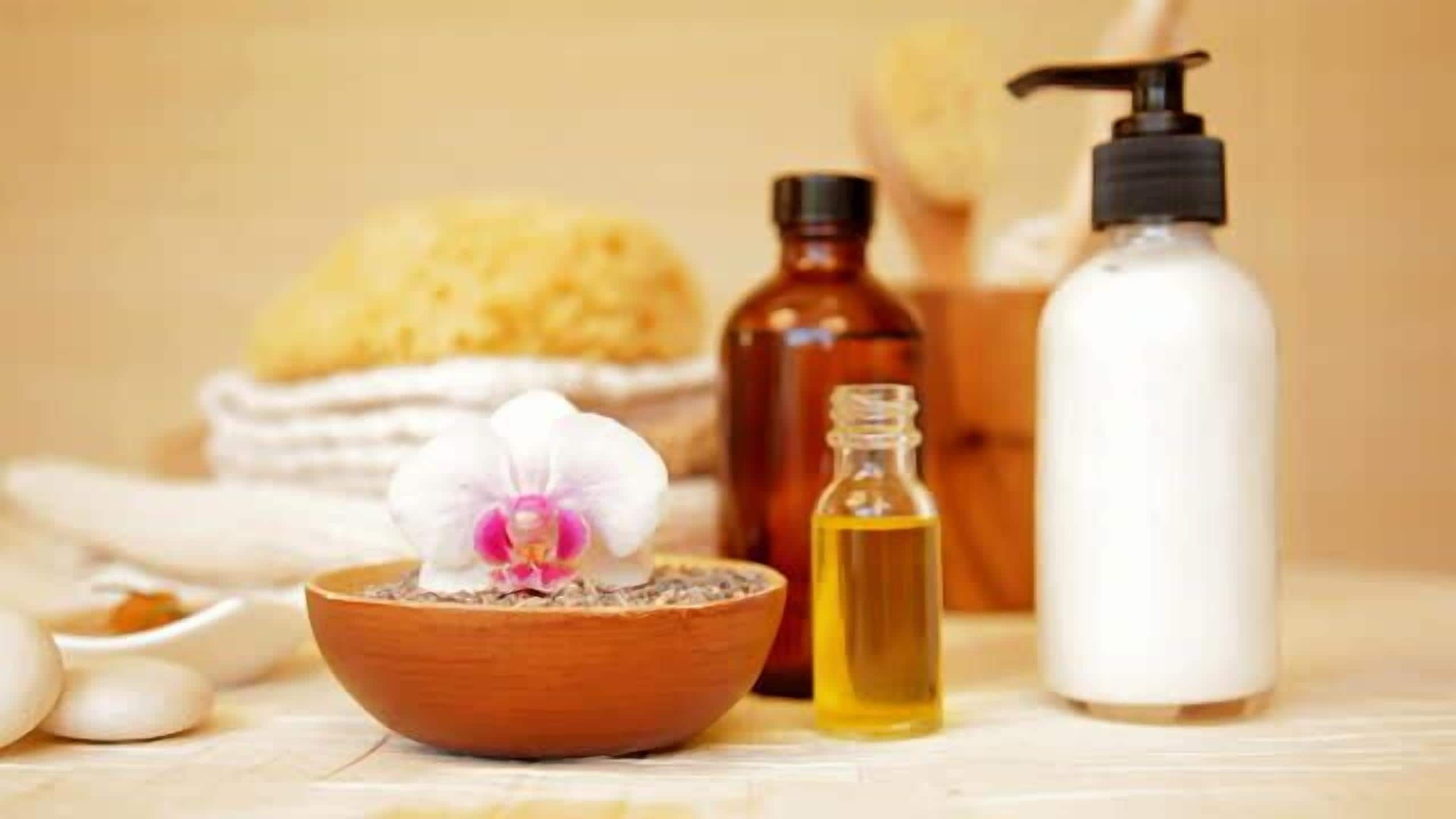 Un entorno de spa con un cuenco de madera que contiene una flor, una botella de aceite y una botella de loción.