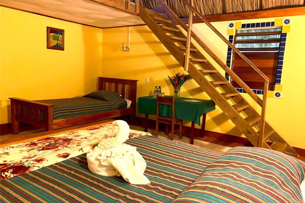 A room with a bunk bed, a small desk with a chair, and a staircase.