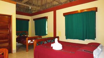 A room with a bed, a wooden bench, and a table with a red tablecloth.