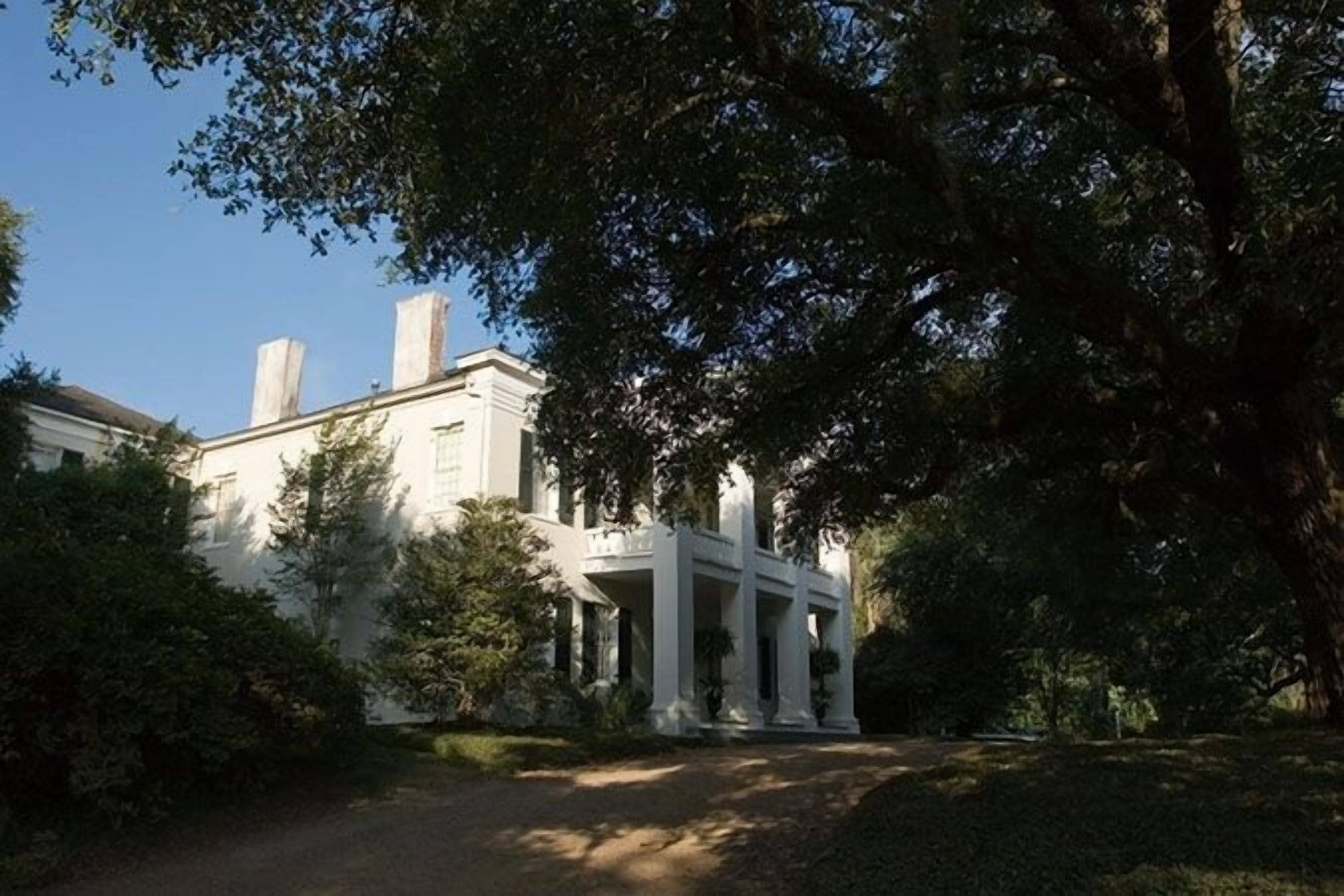 A large, white building with a symmetrical facade, multiple chimneys, and a central entrance with columns.